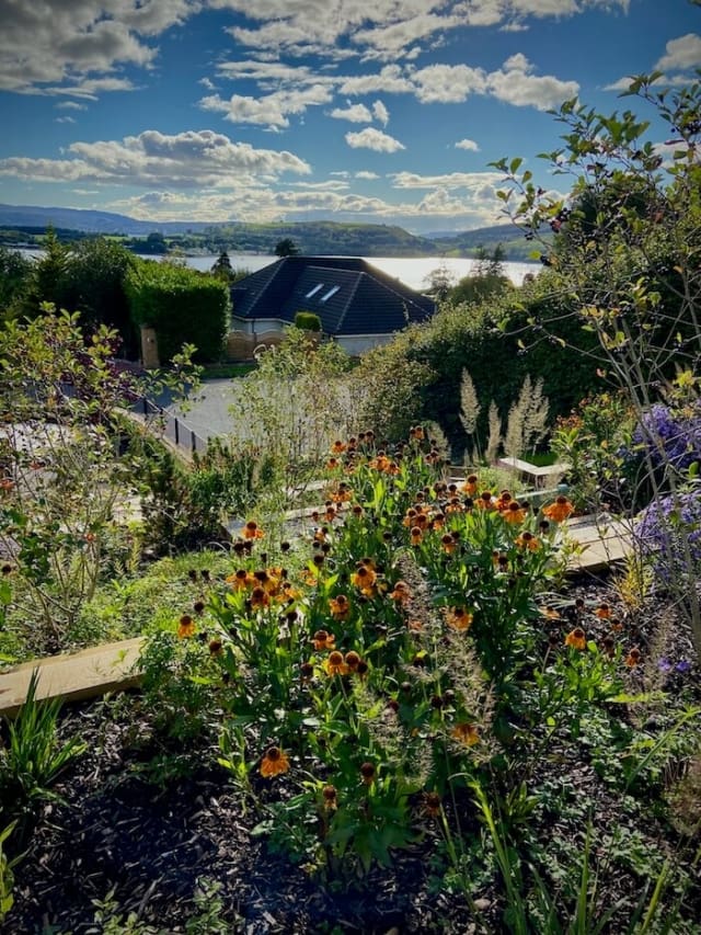 View of flowers and borders in the foreground with the Firth of Clyde in the distance